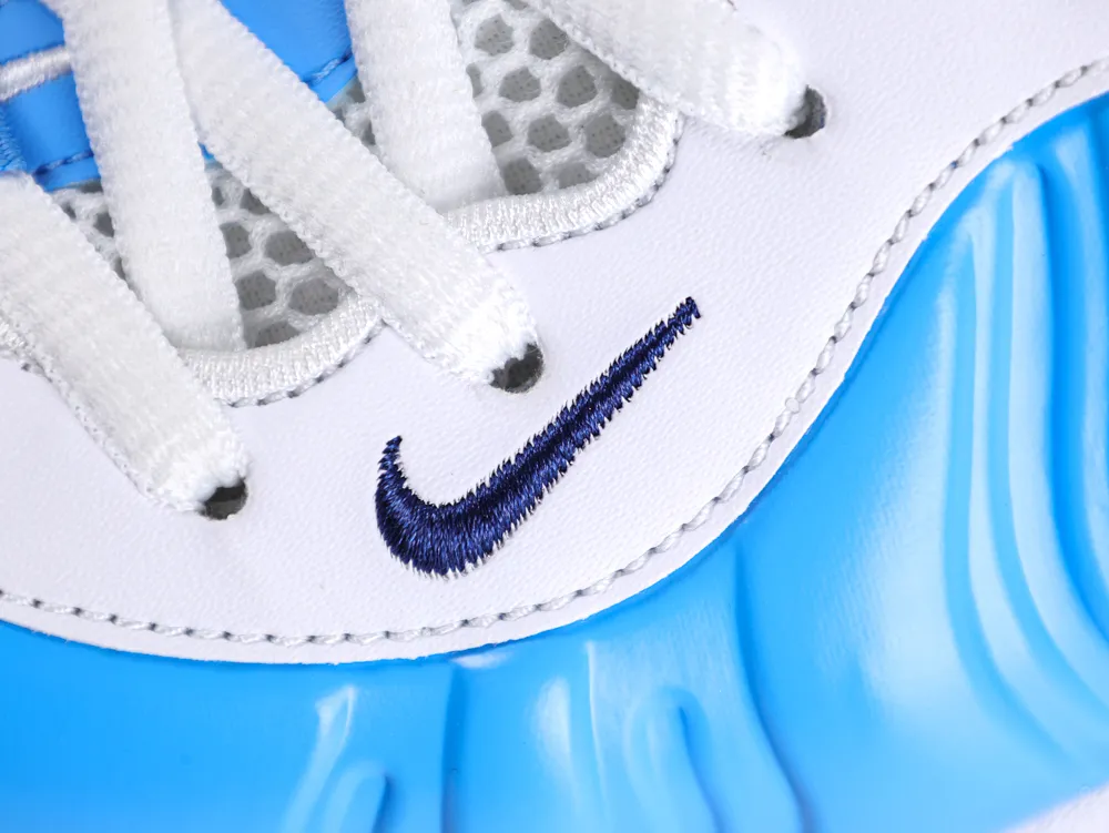 Close-up of a white and blue sneaker with blue stitching, mesh texture, and laces.