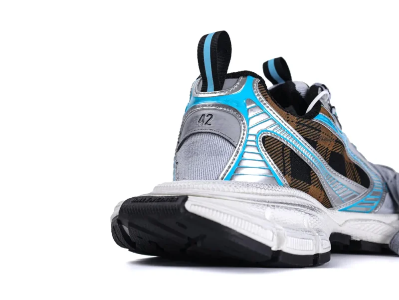 Rear view of a sneaker with blue, silver, and brown accents, rubber sole.