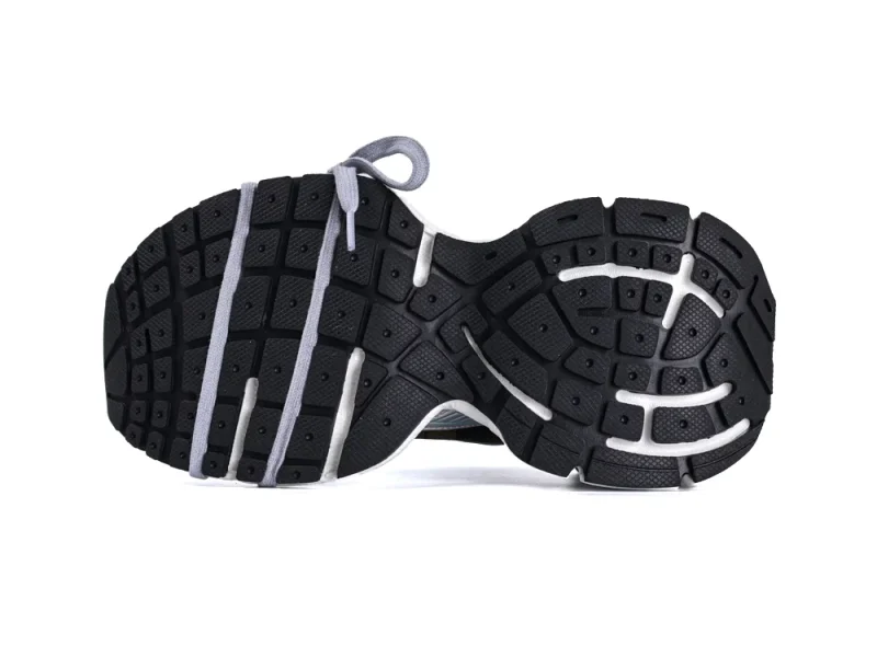 Black rubber shoe sole with white accents, showing textured treads and grey laces.