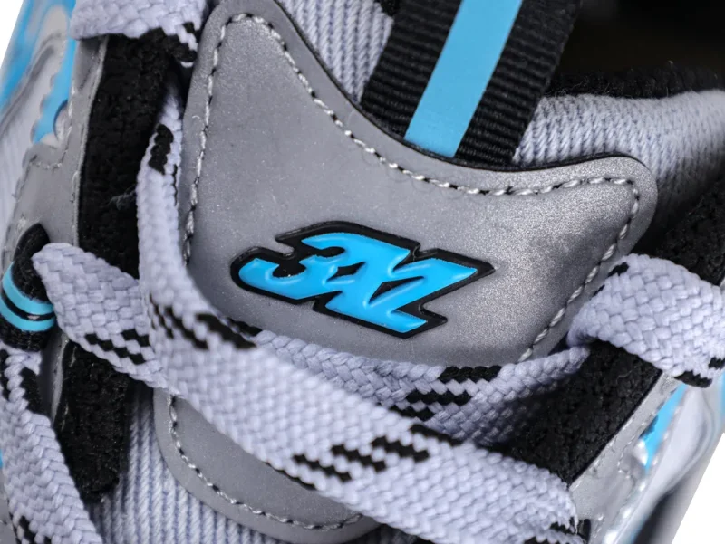 Close-up of gray leather sneaker with blue logo and white-black patterned laces.