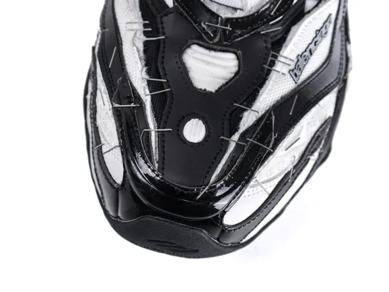 Close-up of a black and white sneaker toe, featuring leather and fabric materials.