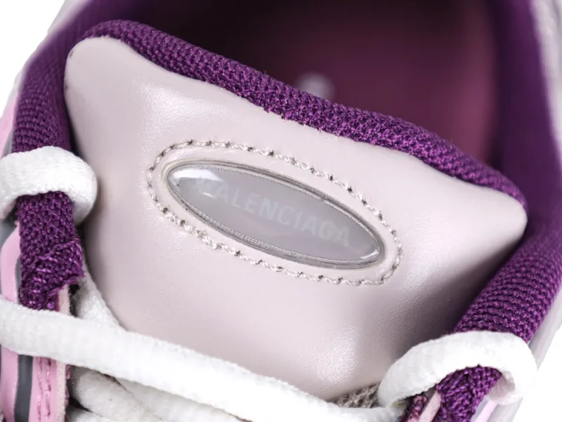 Close-up of pink leather shoe tongue with purple fabric trim and white laces.