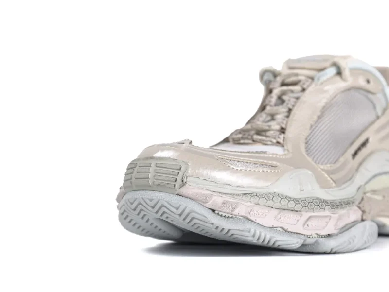 Close-up of beige sneaker with leather and mesh materials, showcasing the sole and laces.