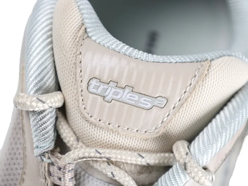 Beige and silver fabric sneaker tongue with logo and textured laces.