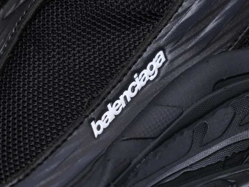 Close-up of a black mesh sneaker with embossed plastic detailing and brand logo.