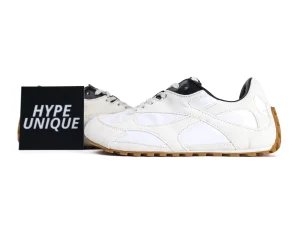 White and black suede sneakers with gum soles displayed beside a "Hype Unique" sign.
