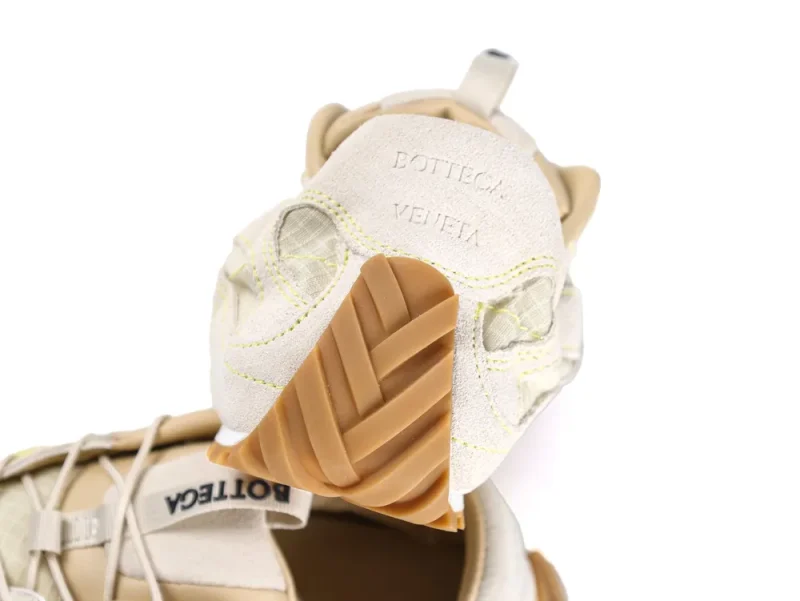 Beige suede sneaker with rubber sole, intricate stitching, and transparent mesh details.