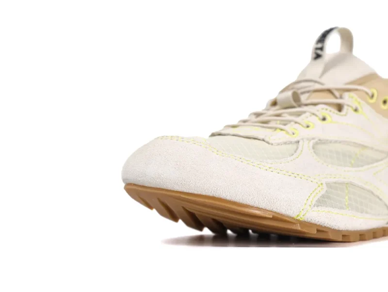 Cream suede sneaker with mesh panels and brown sole, featuring yellow stitching.