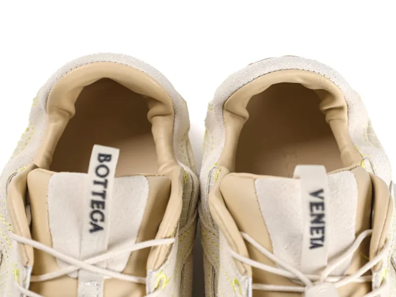 Beige sneakers with suede material and visible tongue tabs displaying brand name.