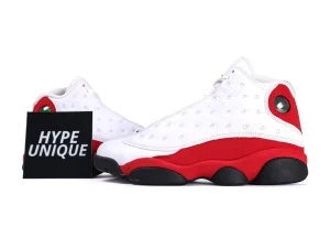 White leather sneakers with red suede accents and black rubber soles.