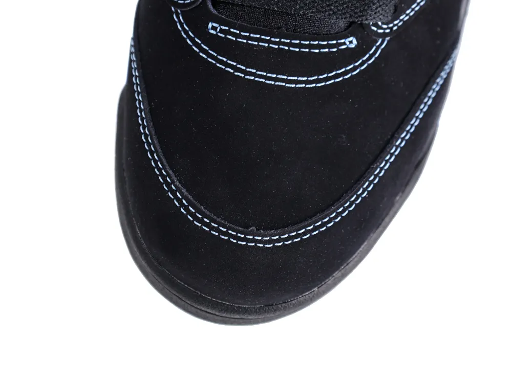 Close-up of black suede shoe toe with blue stitching detail.
