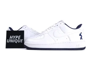 White leather sneakers with dark blue detailing, seen from the side.
