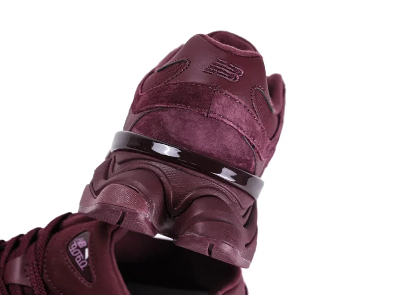 Burgundy suede sneaker with shiny accent and textured rubber sole, close-up view.