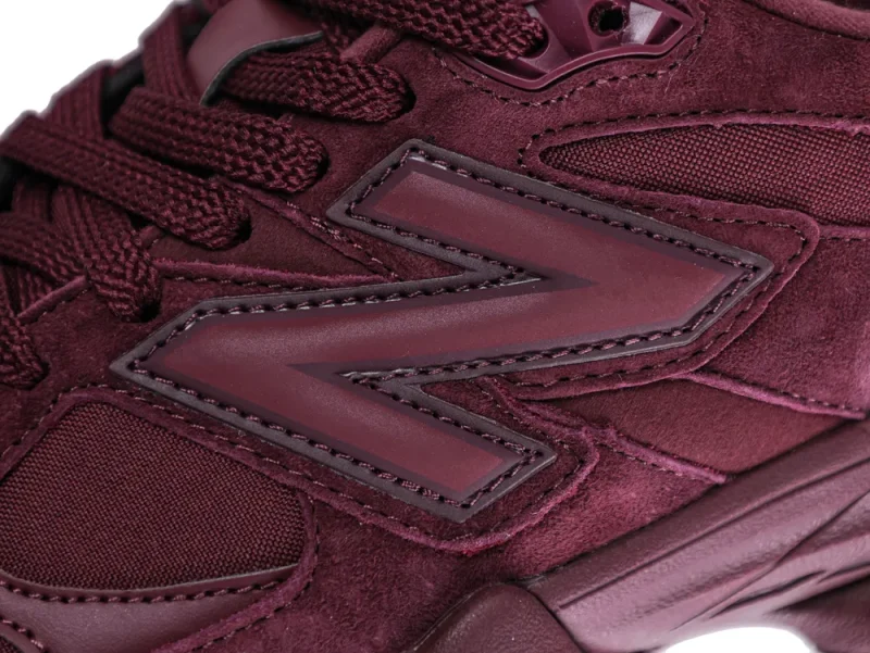 Close-up of burgundy suede sneaker with rubber accents and textured laces.