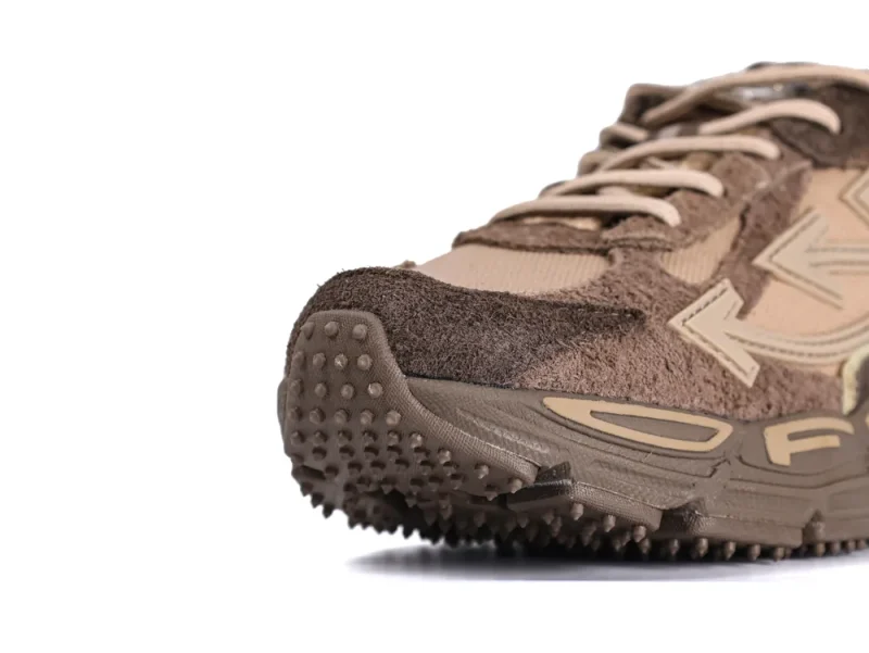 Close-up of brown suede sneaker with textured rubber sole and fabric details.