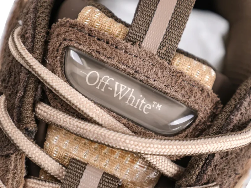 Close-up of brown suede shoe with beige laces and Off-White branding on tongue.