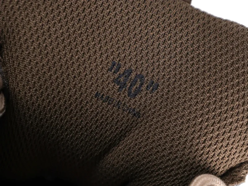 Brown textured fabric with black printed text, part of a glove or garment.