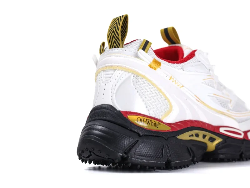 White leather sneaker with black sole, yellow accents, and red mesh lining.