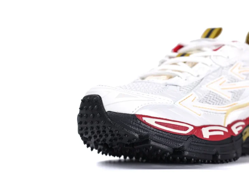 White and red mesh sneaker with black textured rubber sole and detailed patterns.