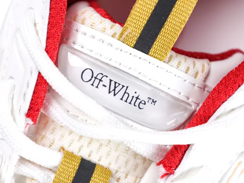 Close-up of a white and red sneaker with yellow laces and fabric mesh.