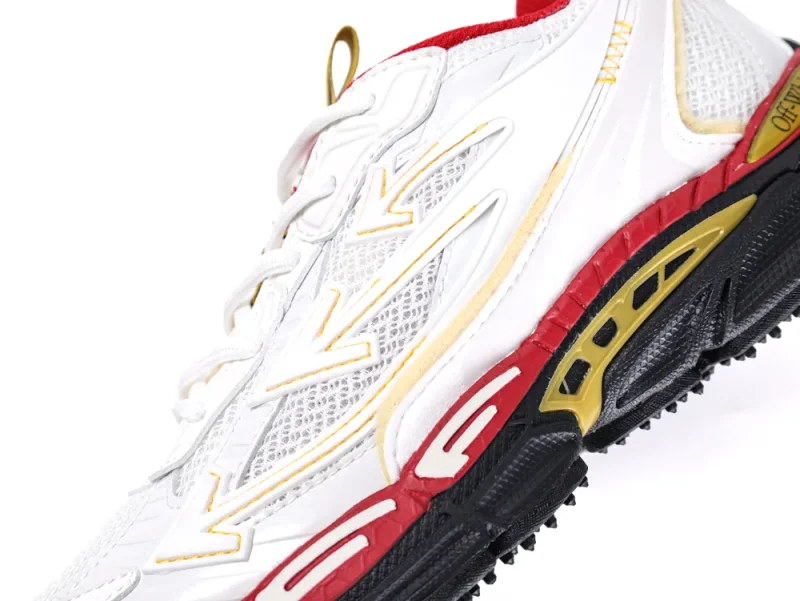 White sneaker with mesh fabric, red and black sole, yellow accents.
