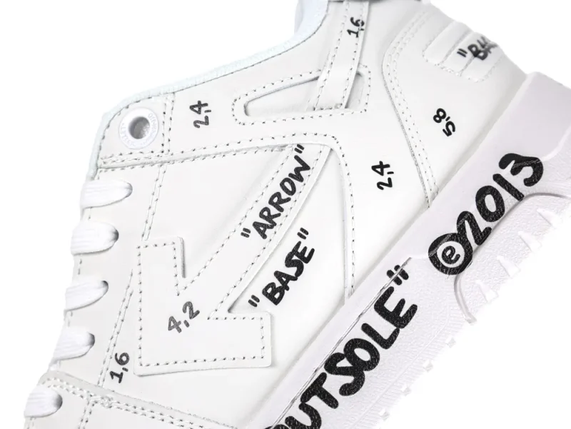 White leather sneaker with black text and arrow design, emphasizing side and sole.