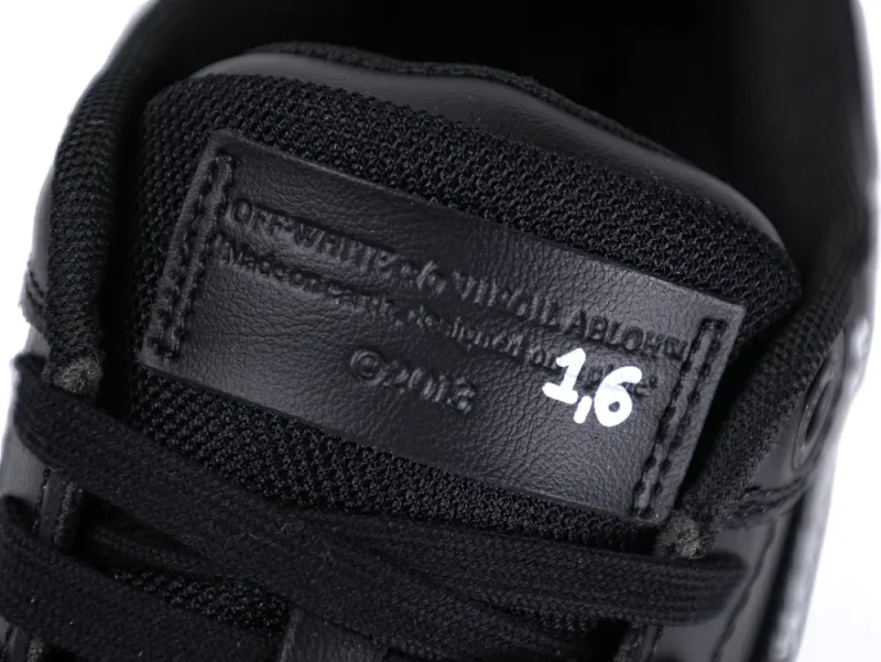 Close-up of black leather sneaker tongue with embossed text and white numbers.