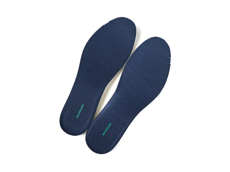 Top-down view of a pair of navy blue Balenciaga sneaker insoles with green logo branding.