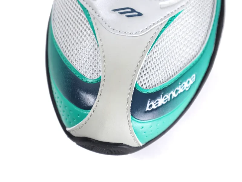 Close-up of the sneaker’s front, highlighting the white mesh upper, green gradient leather overlays, and white "Balenciaga" script.