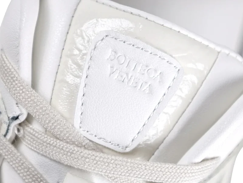 Detailed view of the white leather tongue patch with an embossed Bottega Veneta logo.
