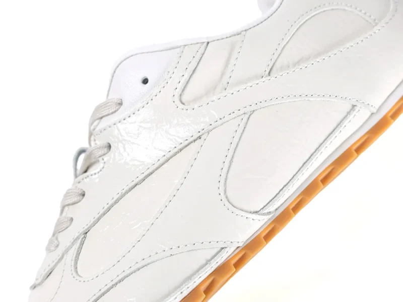 Close-up of the cream patent leather side panels and tonal stitching on the Bottega Veneta Orbit Flash.