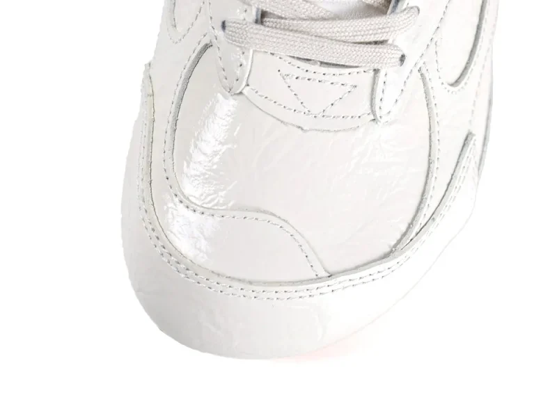 Overhead view of the rounded toe box featuring shiny cream leather and light grey laces.