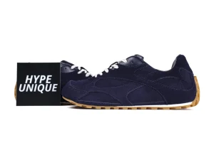 Navy blue suede sneakers with white laces and gum soles, beside "Hype Unique" box.