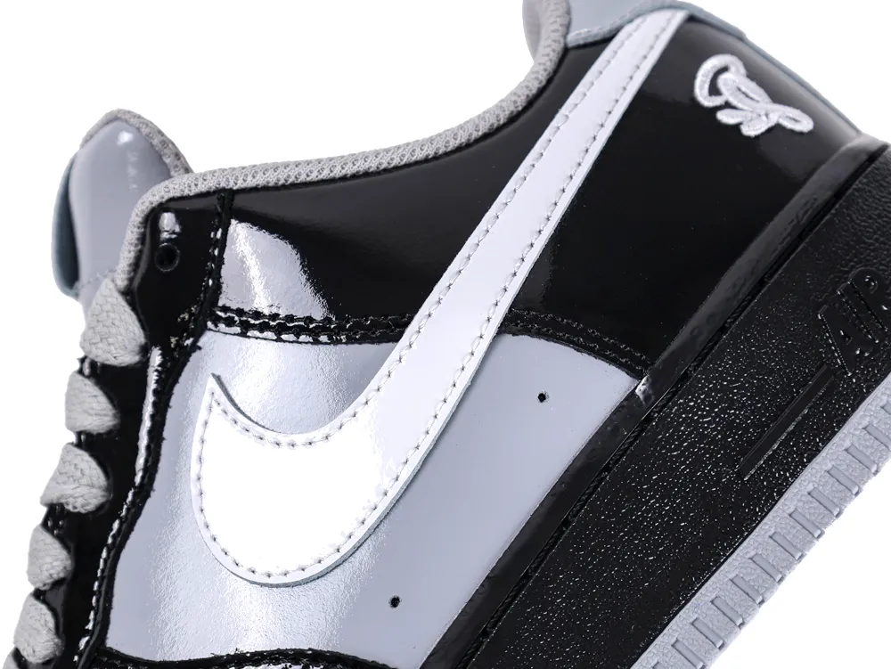 Detailed view of the white leather swoosh against grey and black patent leather panels.