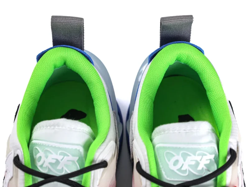 Close-up of sneakers with green fabric lining, gray pull tabs, and white tongues.